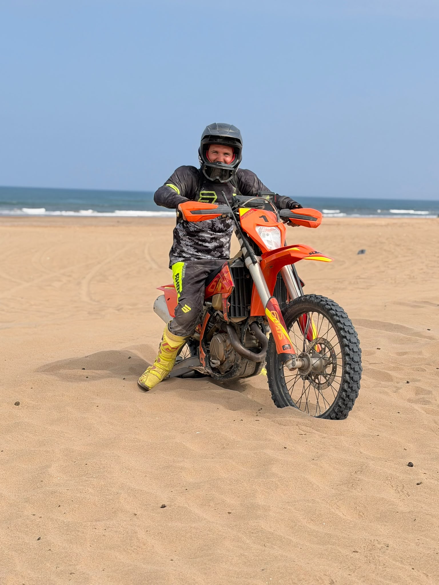 Pilote enduro en pleine accélération sur la plage d'Agadir, écume et sable projetés par la KTM